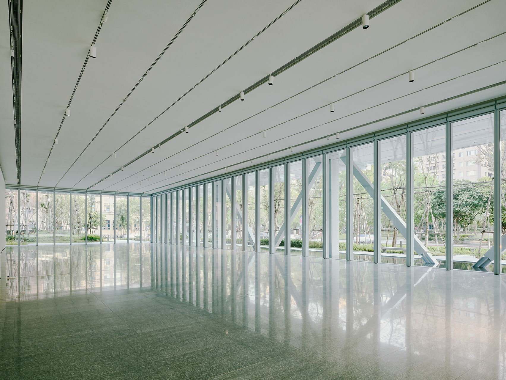 美術館一樓「水景展廳」挑高六米、無立柱阻隔，三面玻璃帷幕設計使其具備穿透與輕盈，與戶外的自然植層和淺水池面相互映射流動，展現視覺連接與開闊的展場空間。（攝影：Lucas K. Doolan）